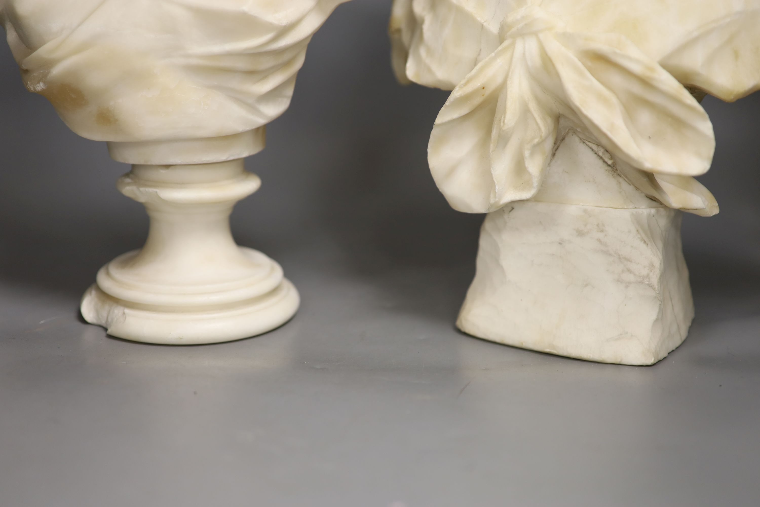 Two white alabaster busts of young women, raised on turned plinths 44cm